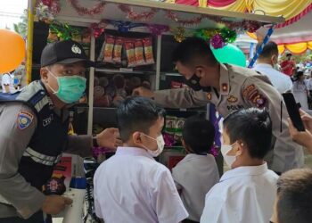 Personel membagikan makanan ringan kepada para siswa SD