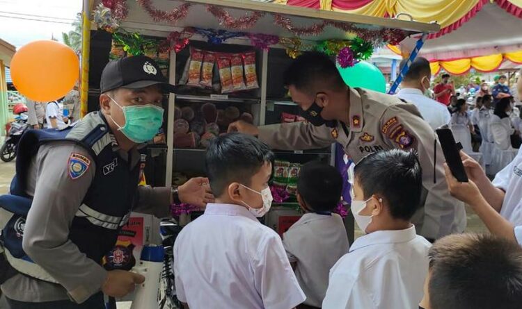Personel membagikan makanan ringan kepada para siswa SD