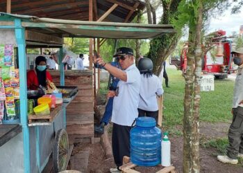 Camat Pahandut, Berlianto (baju putih dan bertopi), saat melakukan sosialisasi kepada PKL tentang penataan bangunan di atas drainase.