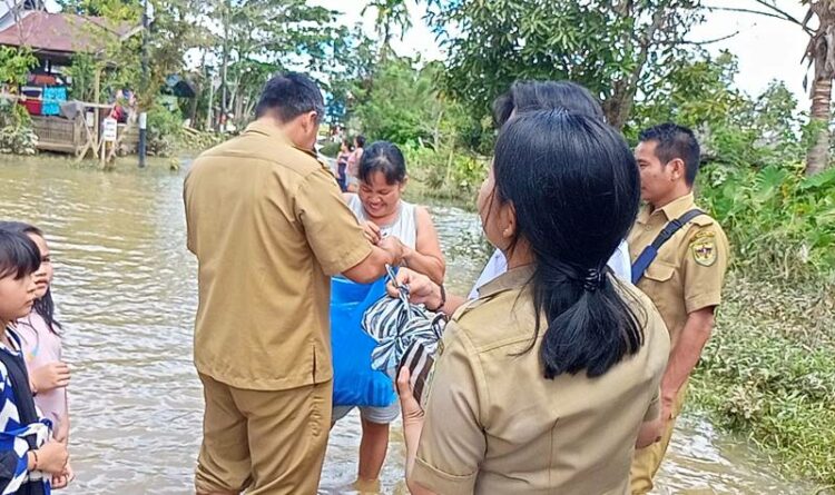 Kepala Dispertan Gumas Letus Guntur bersama sekretaris Hengki Panto dan kabidnya sedang menyerahkan bantuan nasi bungkus dan sembako ke warga terdampak banjir di Kelurahan TTA, Selasa (6/9).