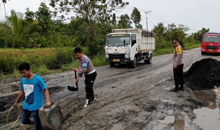 Tampak Anggota Polsek Kurun tengah memperbaiki jalan yang rusak dilalui kendaraan truk yang sering antri di ruas Kurun Palangka Raya, Selasa (28/3).