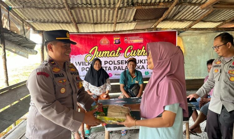 Teks Poto: Kapolsek Bukit Batu, Ipda Iwan Kushadinoto, pada saat menyerahkan beras kepada warga.