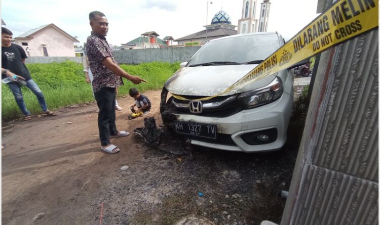 Pemilik mobil, Fitriadi, pada saat menunjukkan bagian mobilnya yang terbakar