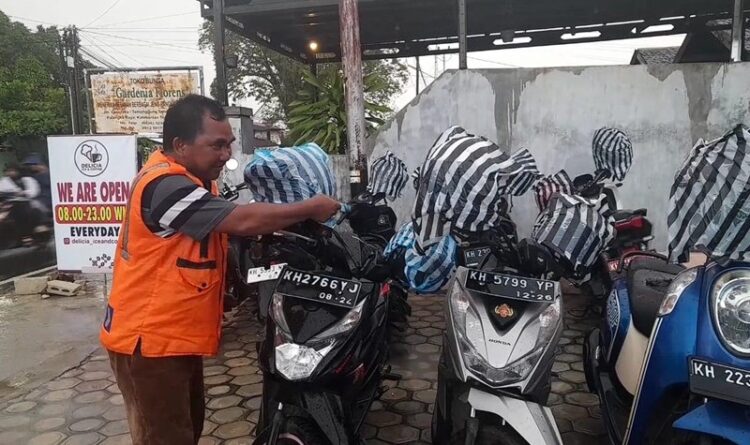 Jukir Di Palangka Raya Bungkus Helm Dengan Plastik Saat Hujan